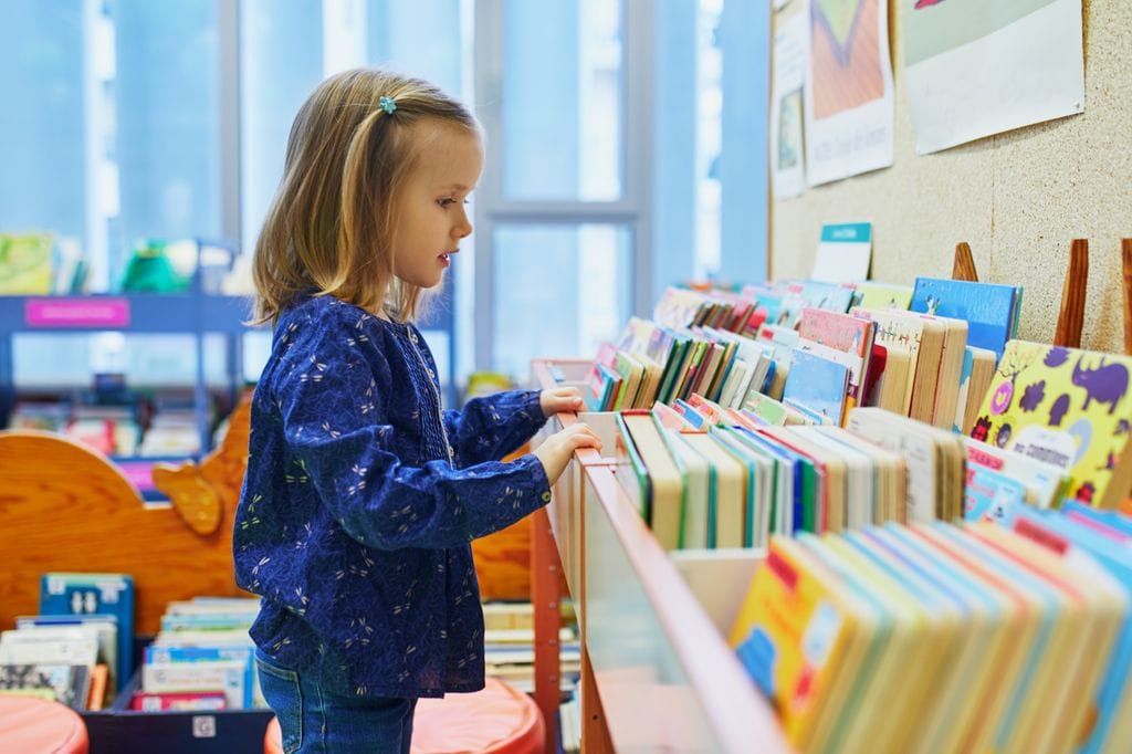 Niña buscando libros en una biblioteca