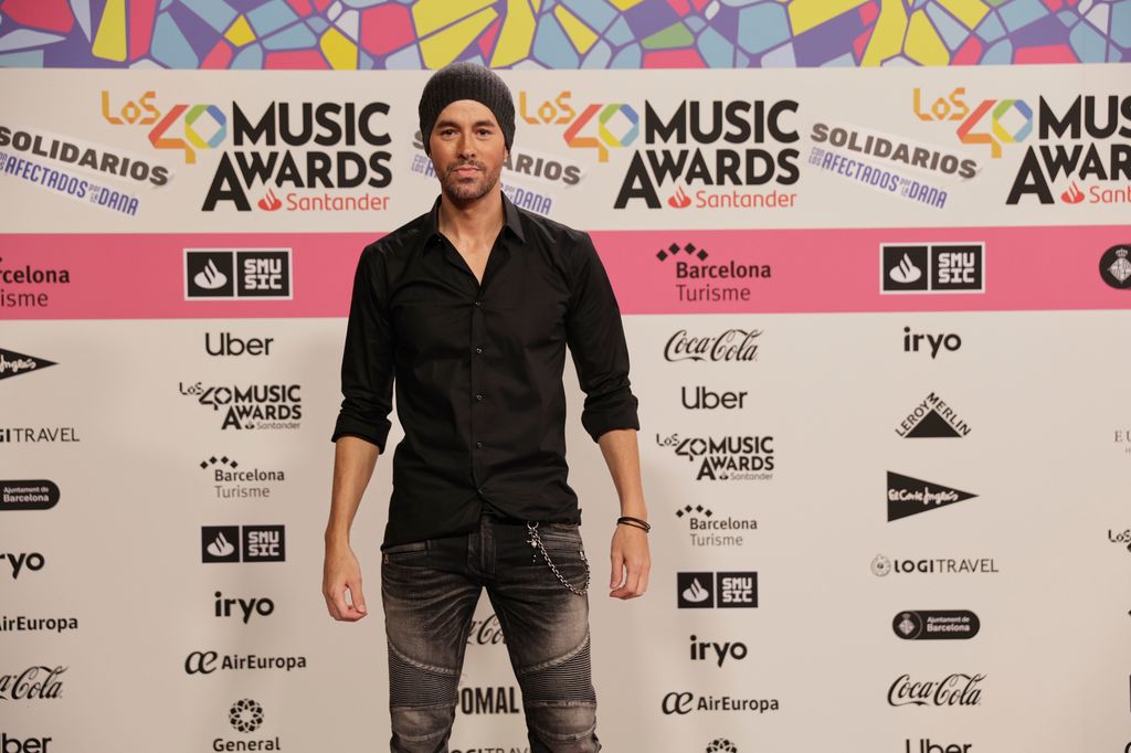 Plano medio de Enrique Iglesias con camisa negra y jeans con cadena