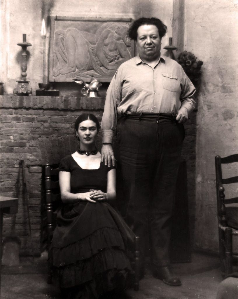 Frida Kahlo sentada y Diego Rivera de pie a su lado