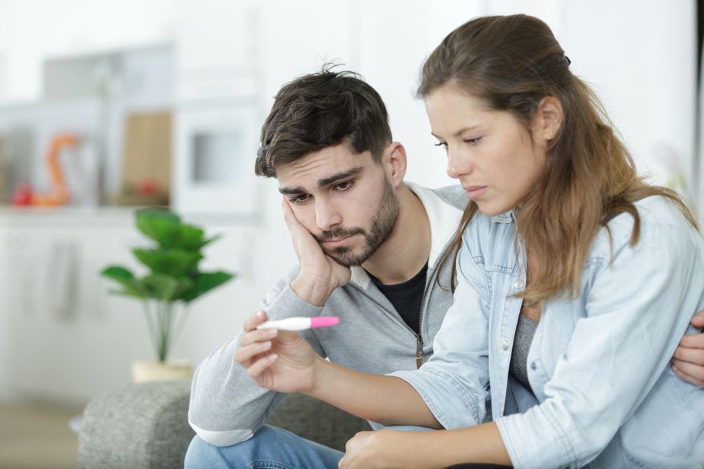 Pareja triste observa el resultado de un test de embarazo