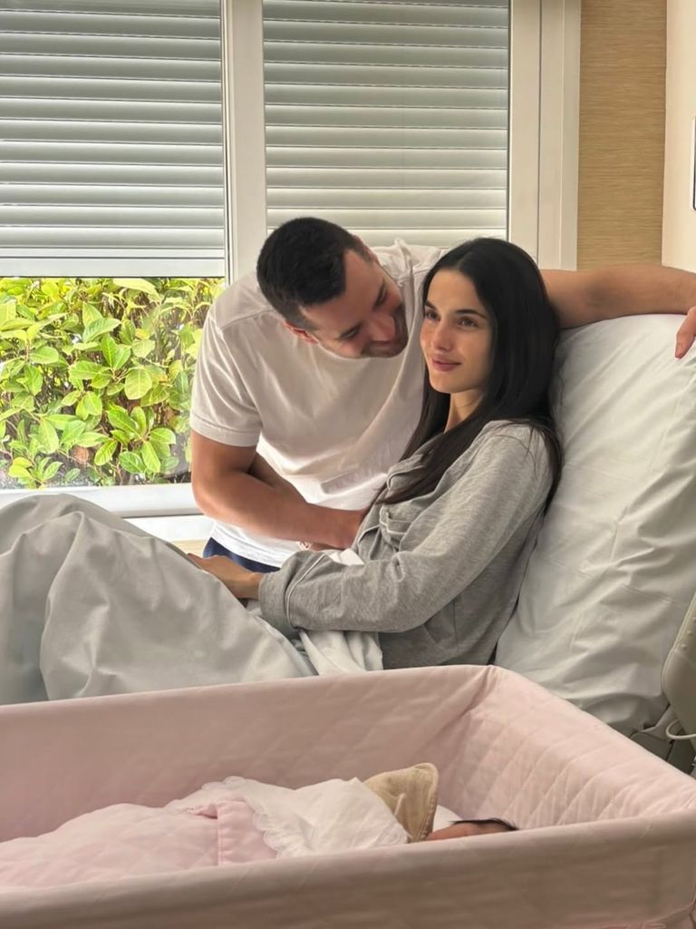 Los felices padres con la bebé en la cunita