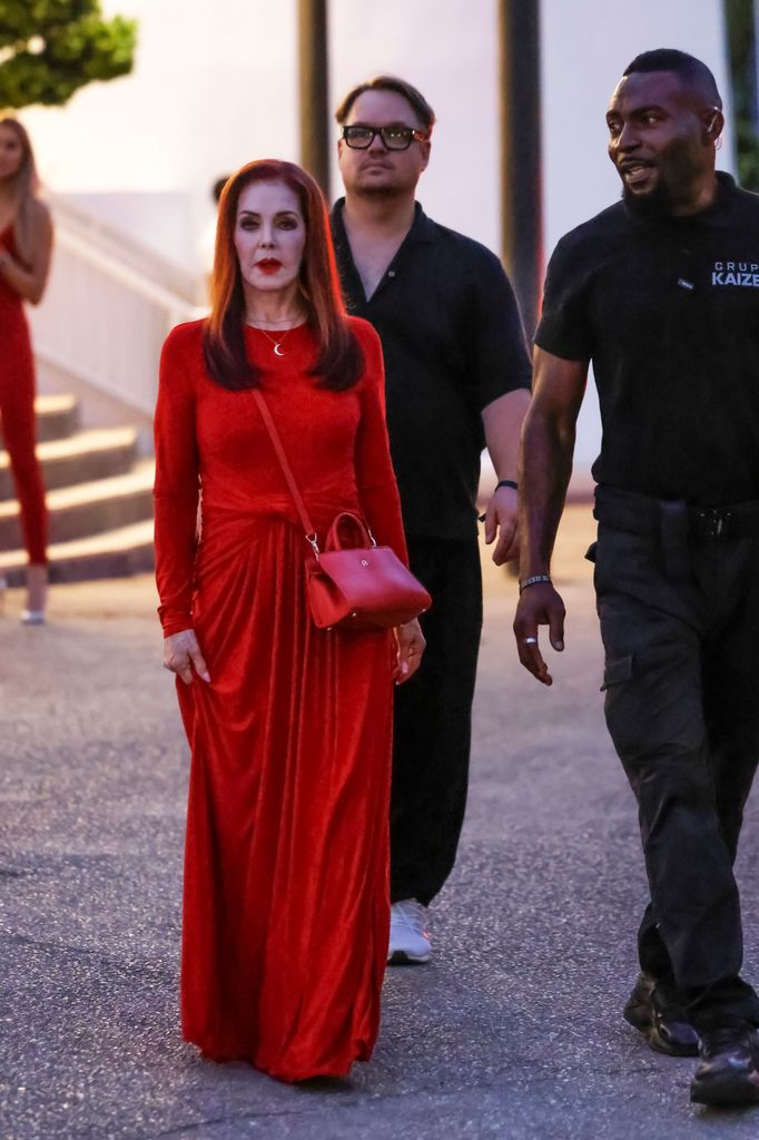 Priscilla llegando al evento en un vestido rojo