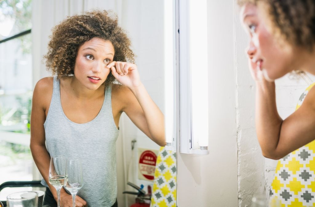mujer mirándose el ojo frente al espejo