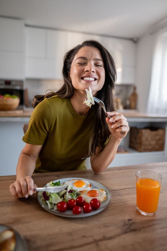 Una mujer con un plato saludable feliz en su cocina