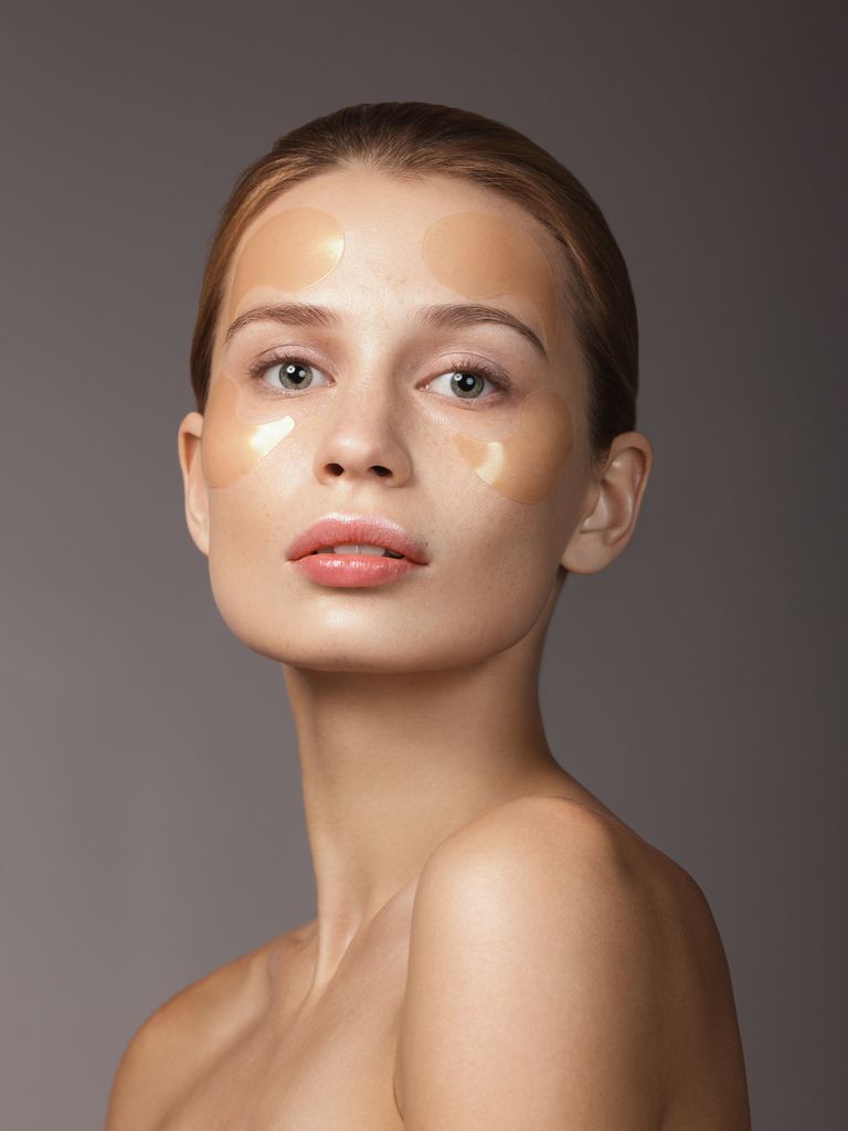 Mujer con parches para ojos sobre el rostro y la piel luminosa