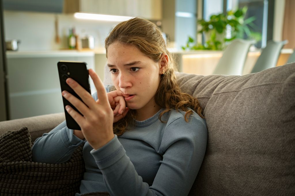 Adolescente preocupada frente al móvil