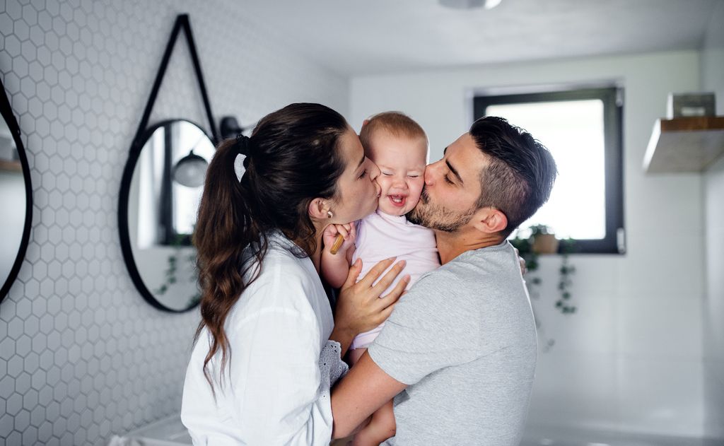 Padres jóvenes dando un beso a su bebé