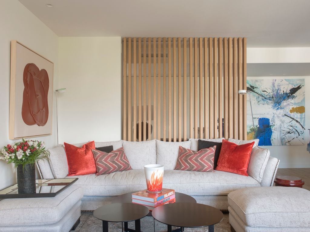 Salón con sofá blanco y cojines en tonos rojos.
