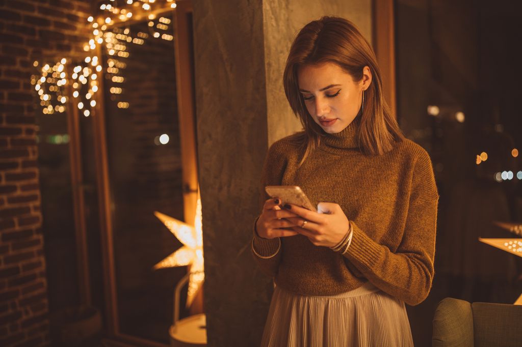 mujer sola en Navidad usando el teléfono móvil