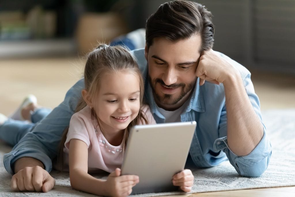 Padre con su hija de 6 años jugando con una tablet