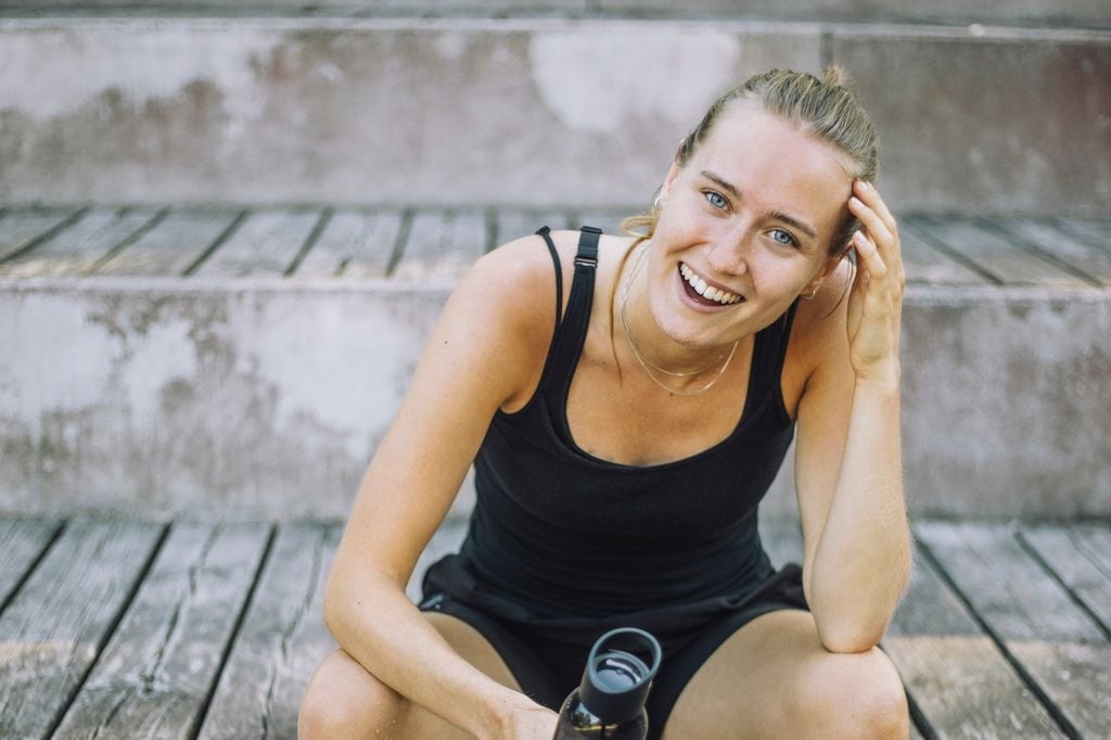 Mujer en ropa deportiva y sonriendo a cámara 