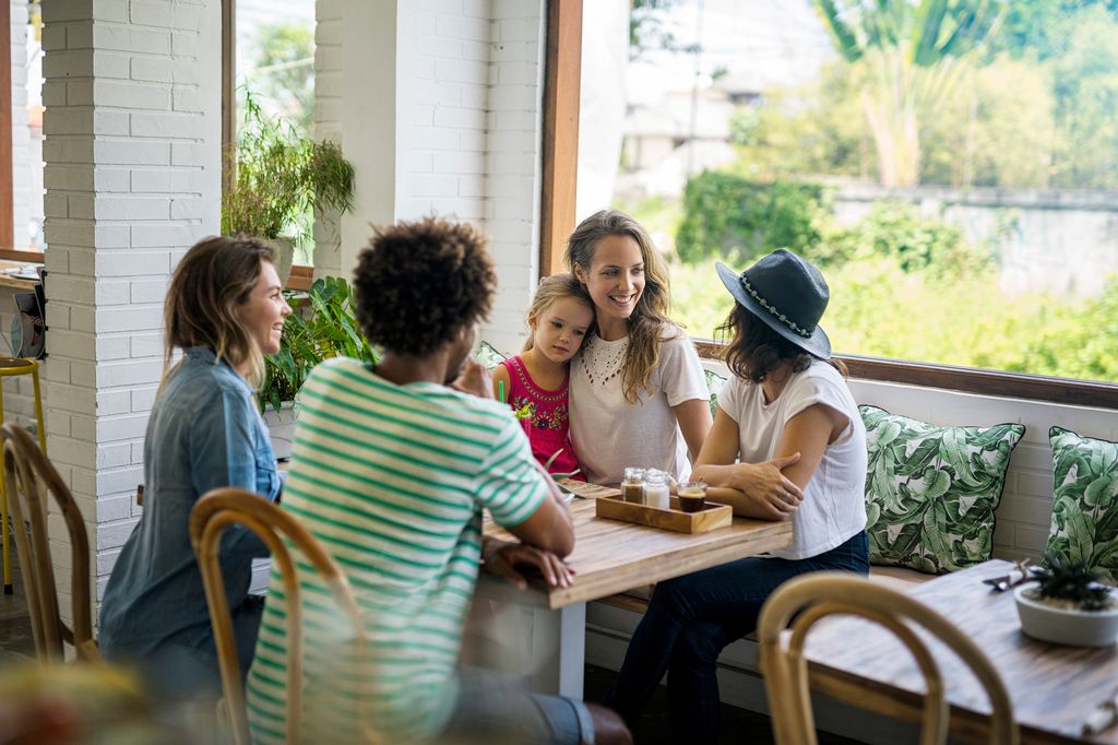 grupo de amigas con un niño, sentadas en una terraza