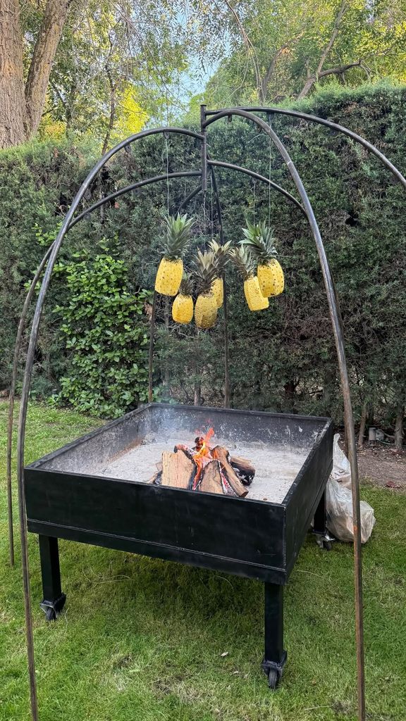 Piñas asándose sobre fuego en una parrilla al aire libre.