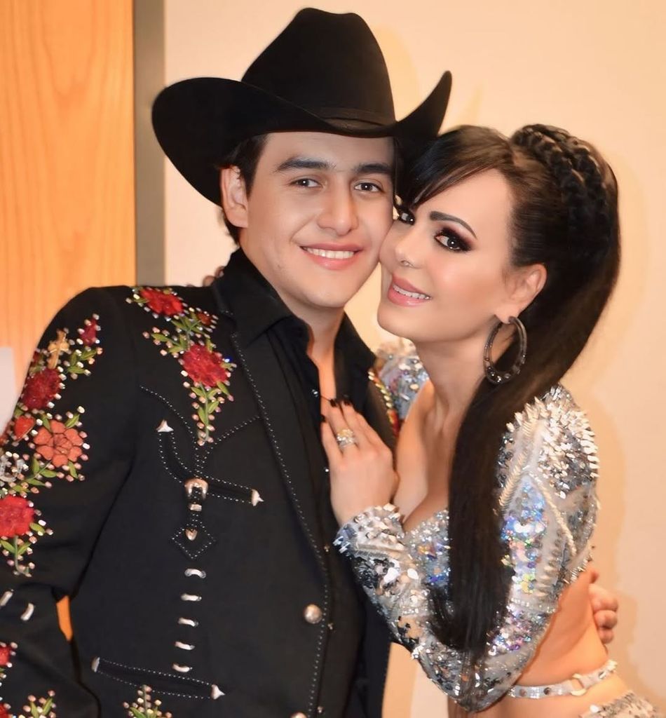 Maribel abraza a un hombre con traje negro y sombrero, ambos sonrientes.