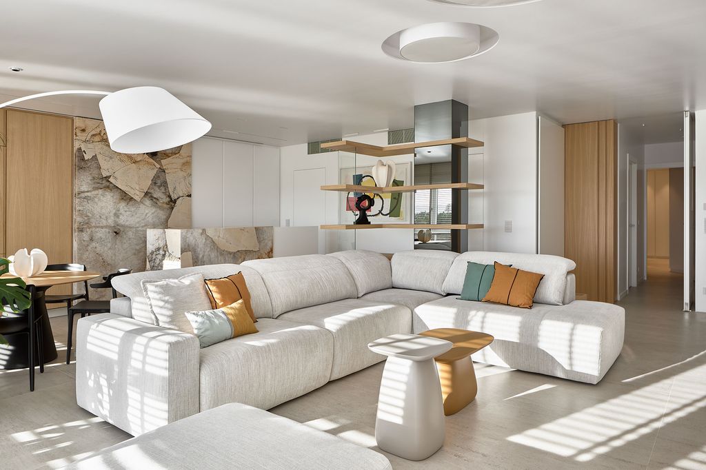 Salón con sofá blanco y cocina con panel corredero. 