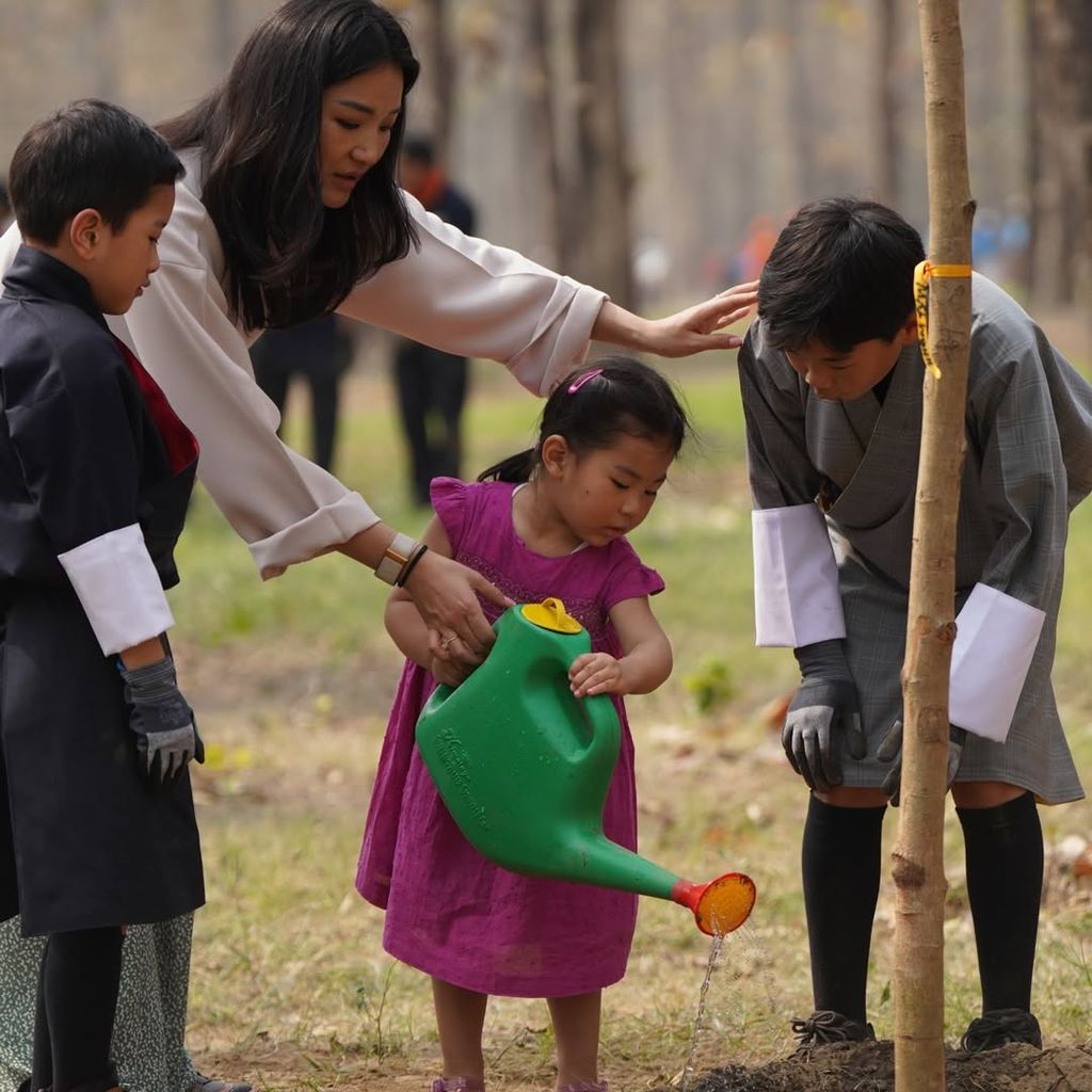 La reina Jetsun junto a sus hijos plantando un árbol