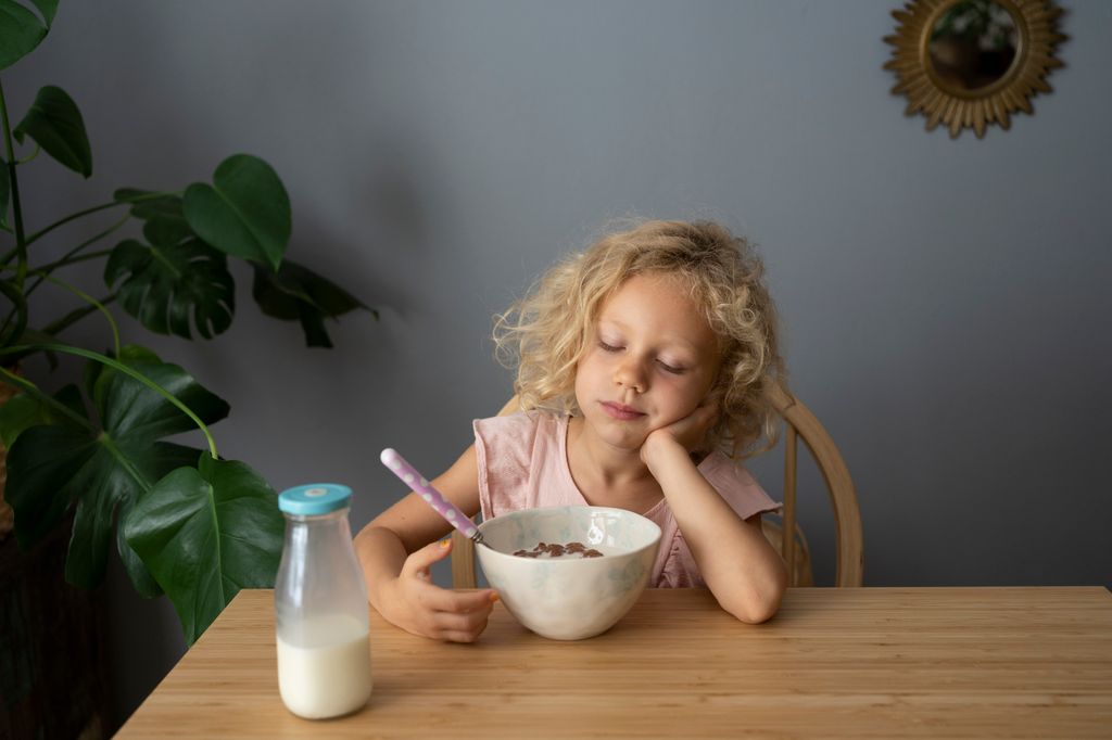 niña desayunando cansada, con poca hambre