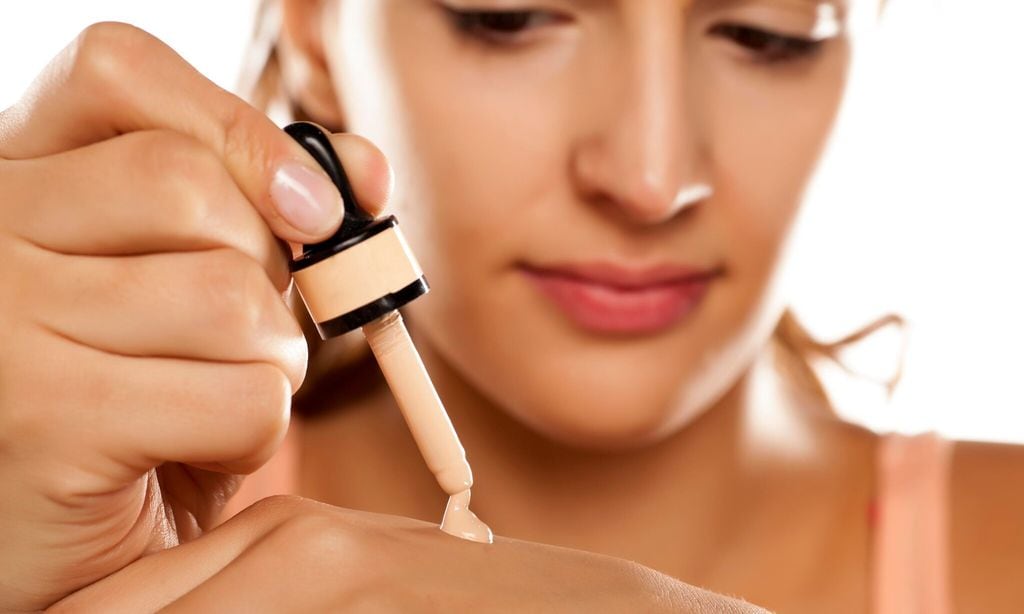 young woman puts a liquid foundation on her palm