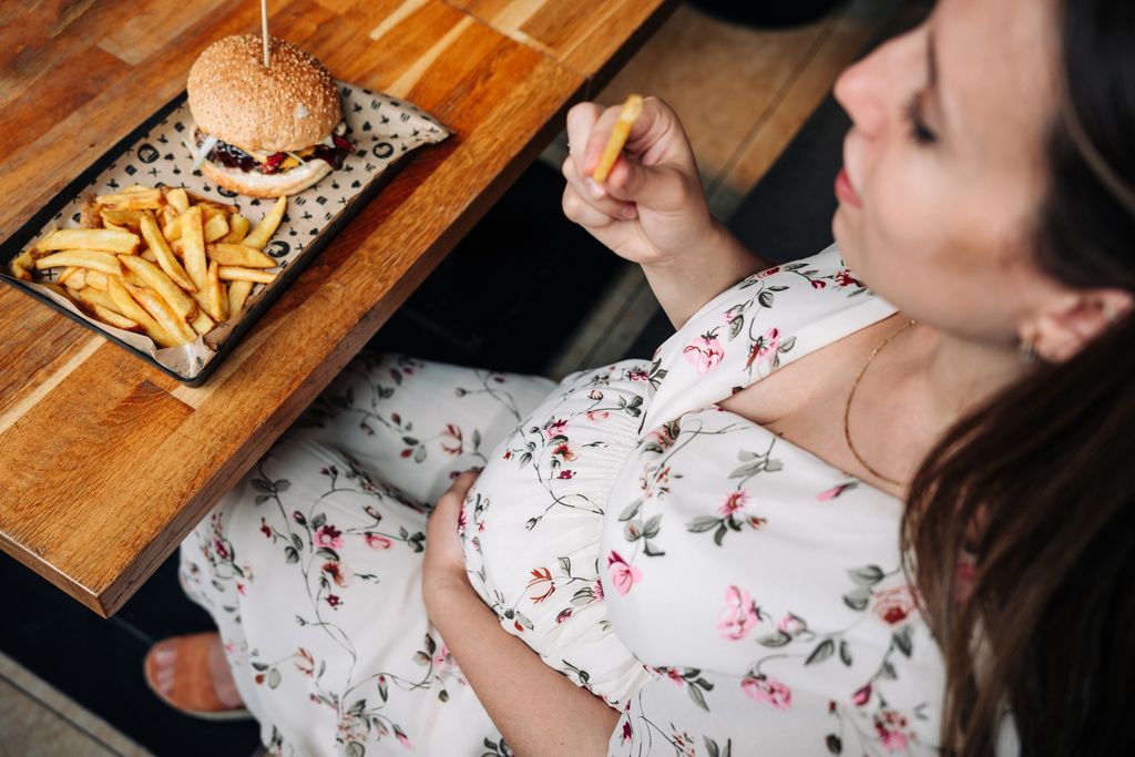 Embarazada tomando una hamburguesa fuera de casa 