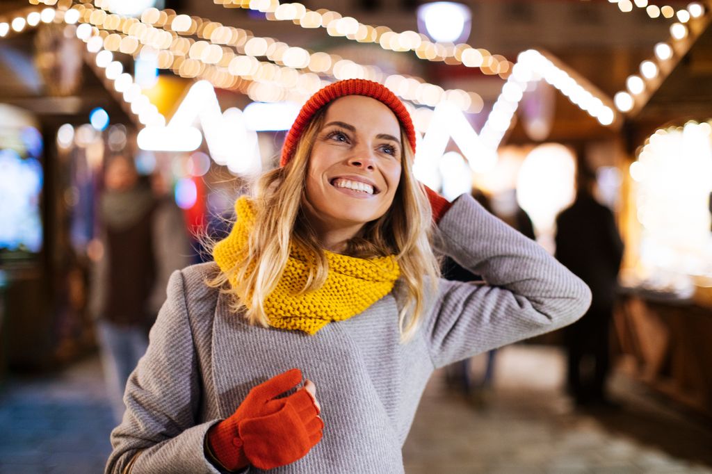mujer abrigada paseando por un mercadillo navideño