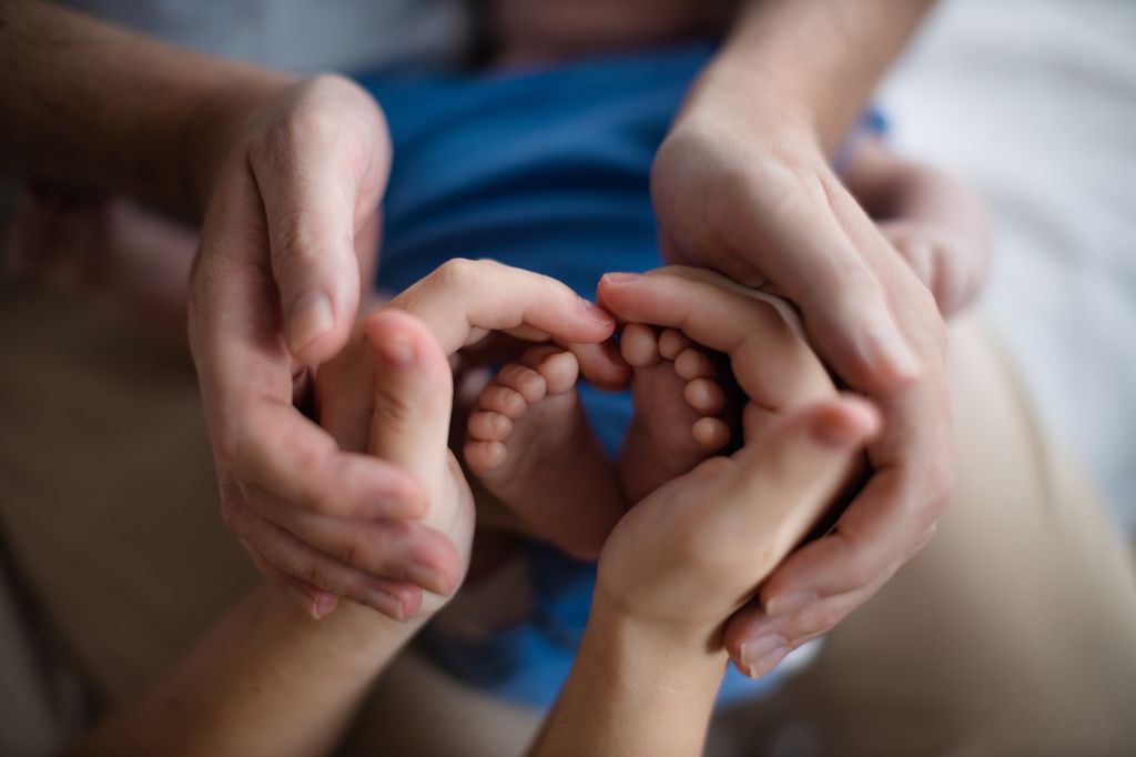 Manos de padre, madre y bebé simulando apoyo posparto