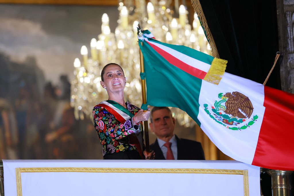 La presidenta Claudia Sheinbaum ondea la bandera de México, en medio de las celebraciones por la Independencia, desde el balcón central de Palacio Nacional.