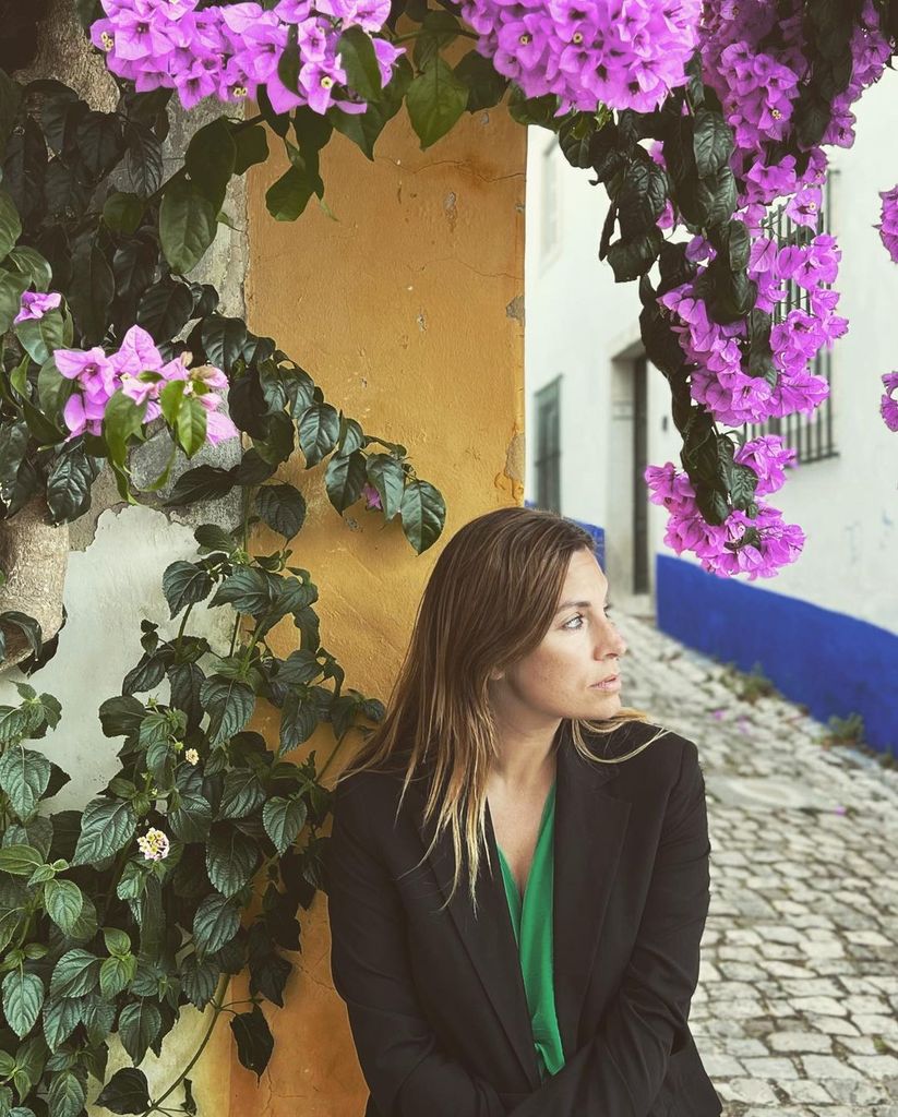 Plano medio de Leire Martínez posando en una calle con flores