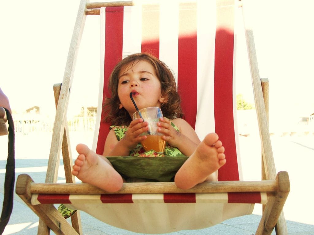 Niña en una tumbona de playa con los pies al aire