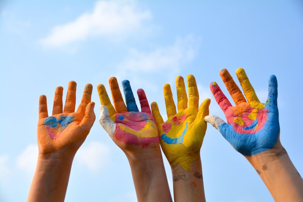 Manos de niños con pintura simulando caras