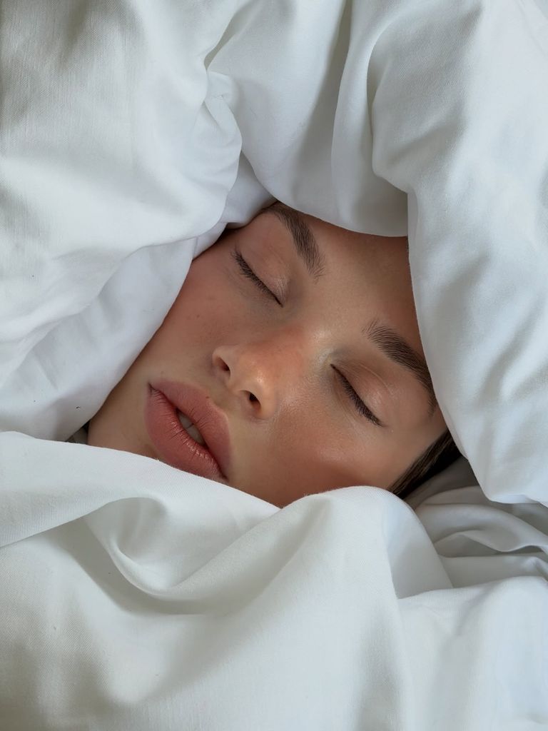 Mujer entre sábanas con los ojos cerrados