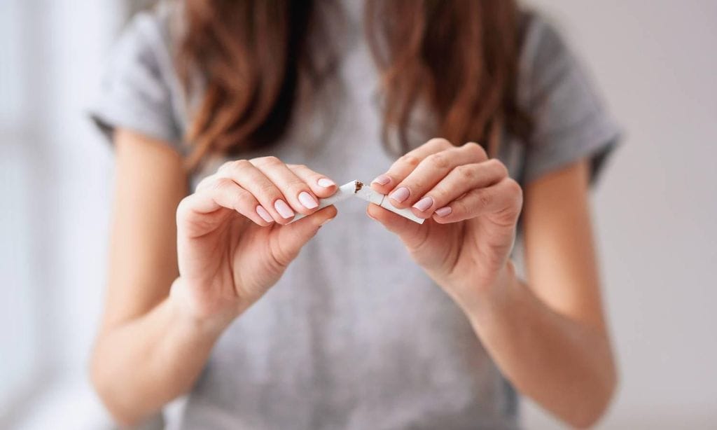 mujer rompiendo cigarrillo con sus dedos