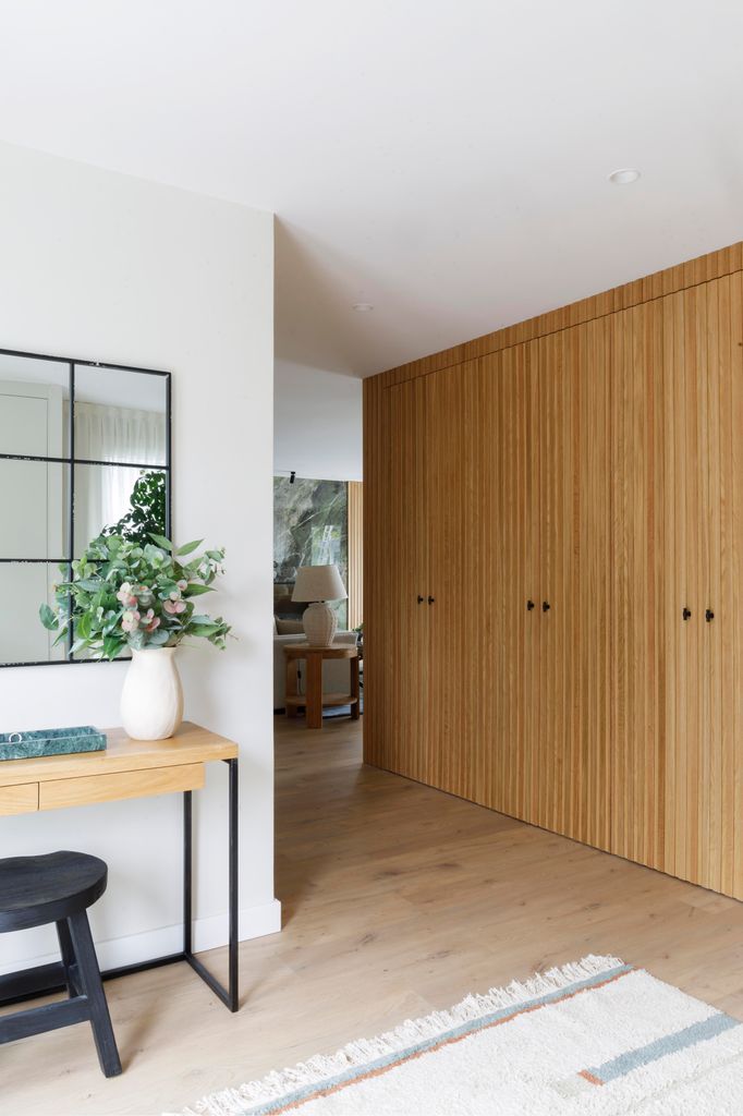 Recibidor con mobiliario bien pensado: consola, espejo y decoración natural a base de un arreglo natural a base de ramas