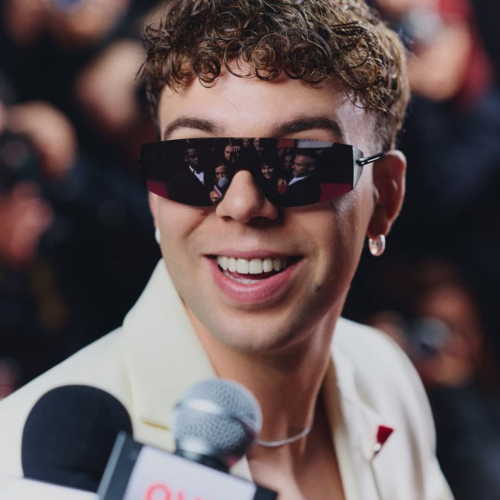 Primer plano de Quevedo con gafas negras y blazer blanca