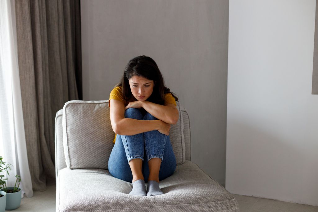 mujer preocupada sentada en el sofá