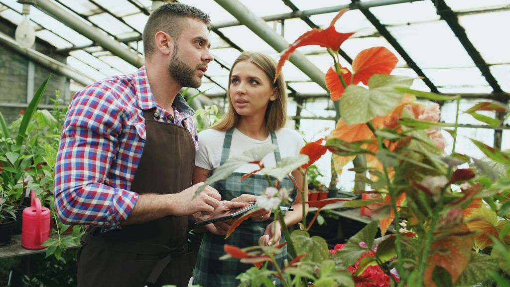 Joven en un vivero seleccionando las plantas para su jardín asesorada por un profesional