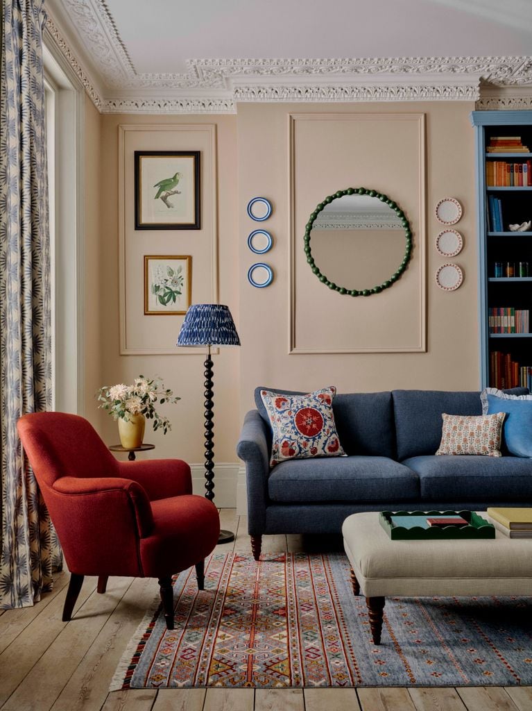 Pared de salón con espejo redondo entre molduras