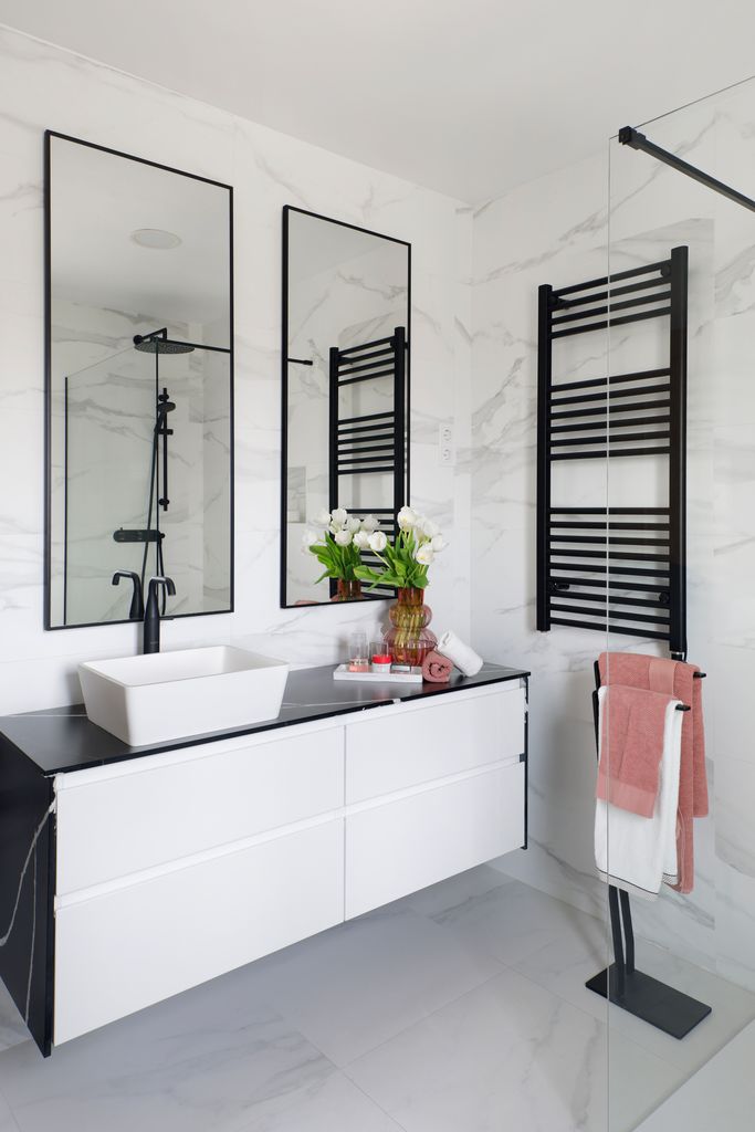 Baño con pocos contrastes, en color blanco con veteado en los revestimientos y elementos negros que aportan carácter