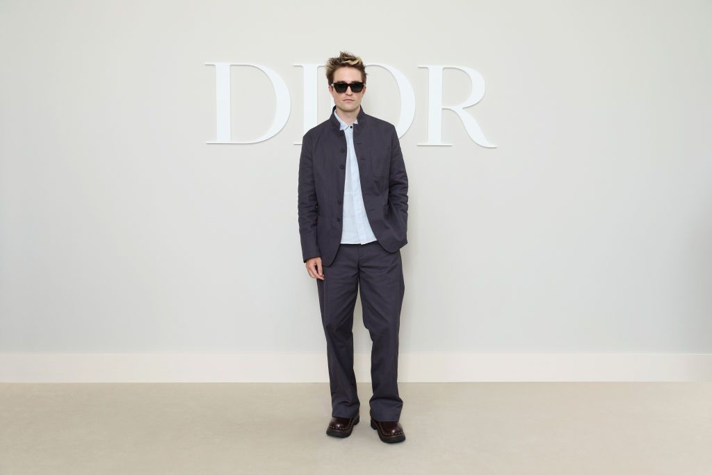 Robert Pattinson apuesta por un traje gris y sin cuello, este lo combina con una camisa azul cielo y zapatos de silueta tipo "chunky".  
