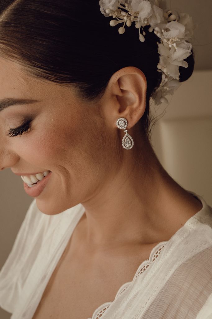 Pendientes de novia y maquillaje y flores en el pelo