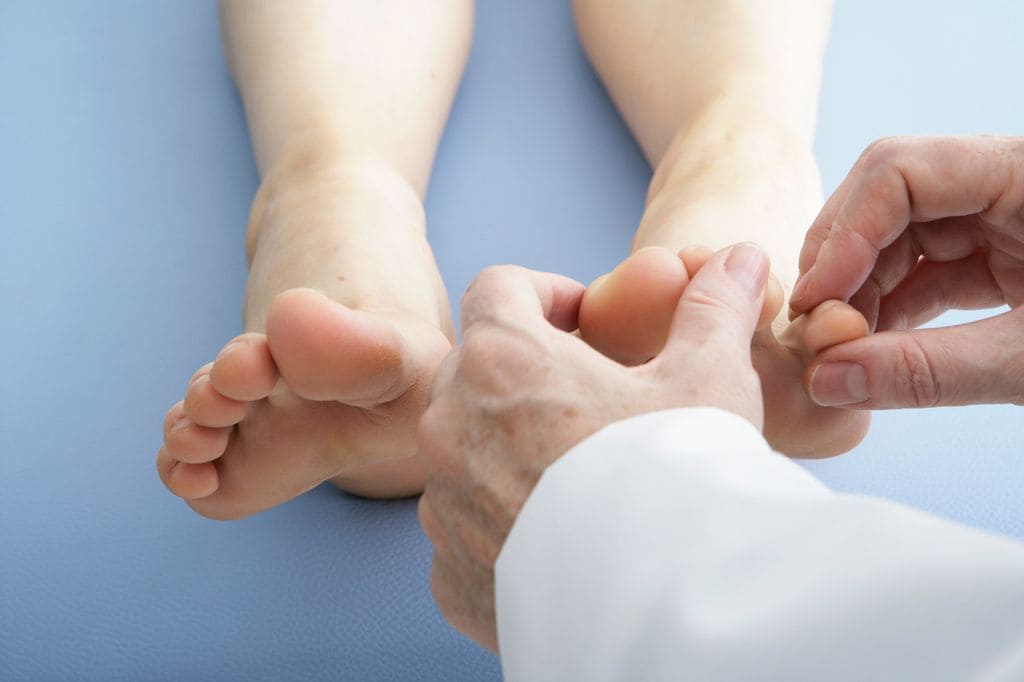 médico observando los pies de una paciente