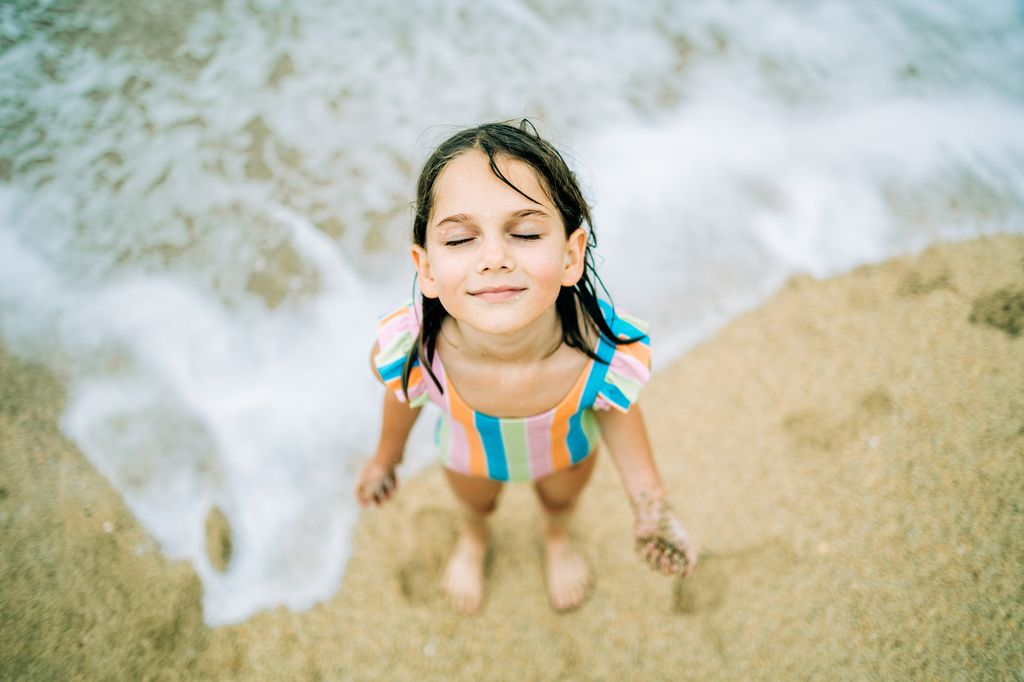 Niña con los ojos cerrados a orillas del mar