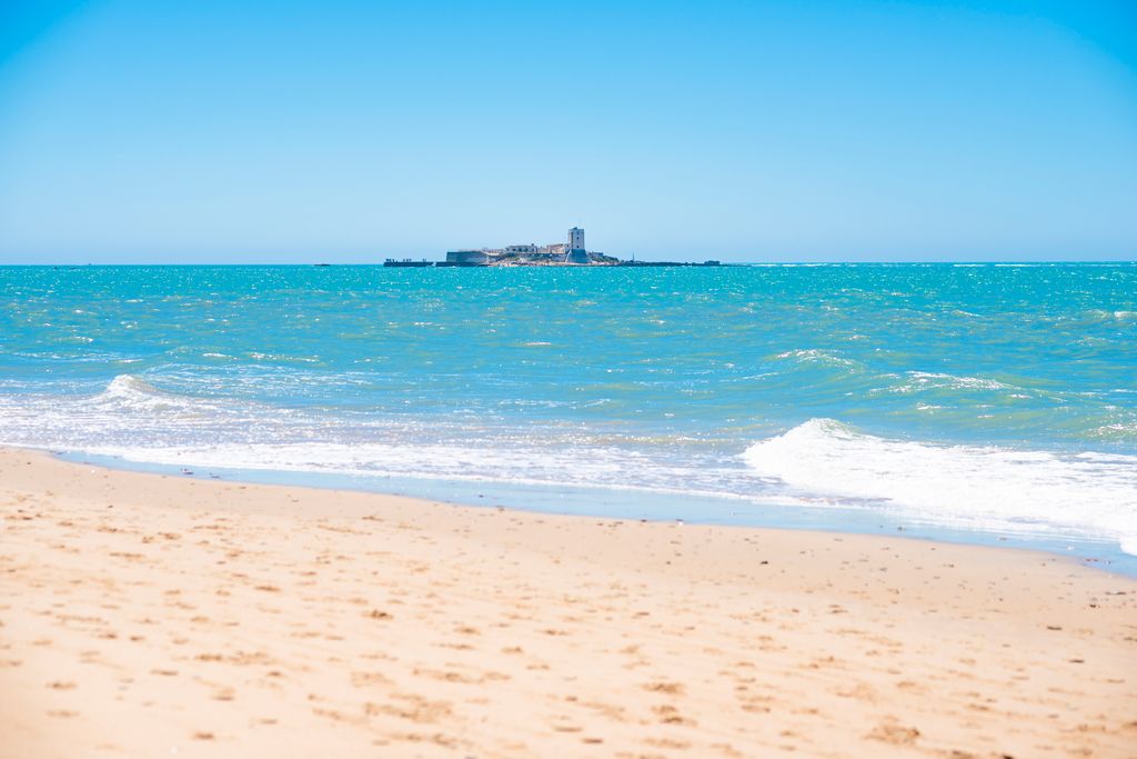 Vista de la playa de La Barrosa, en Cádiz, con el castillo de  Sancti Petri al fondo