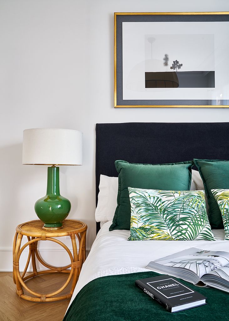 Dormitorio con cabecero azul y mesita de mimbre. 
