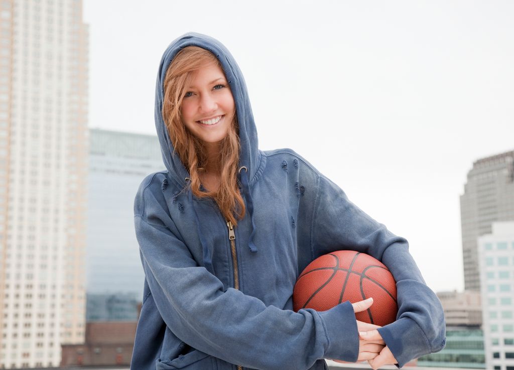 Chica adolescente con capucha y pelota de baloncesto