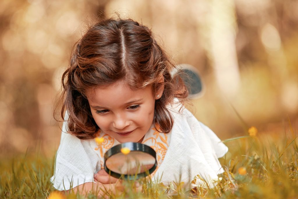 Niña jugando a buscar florecillas en el bosque