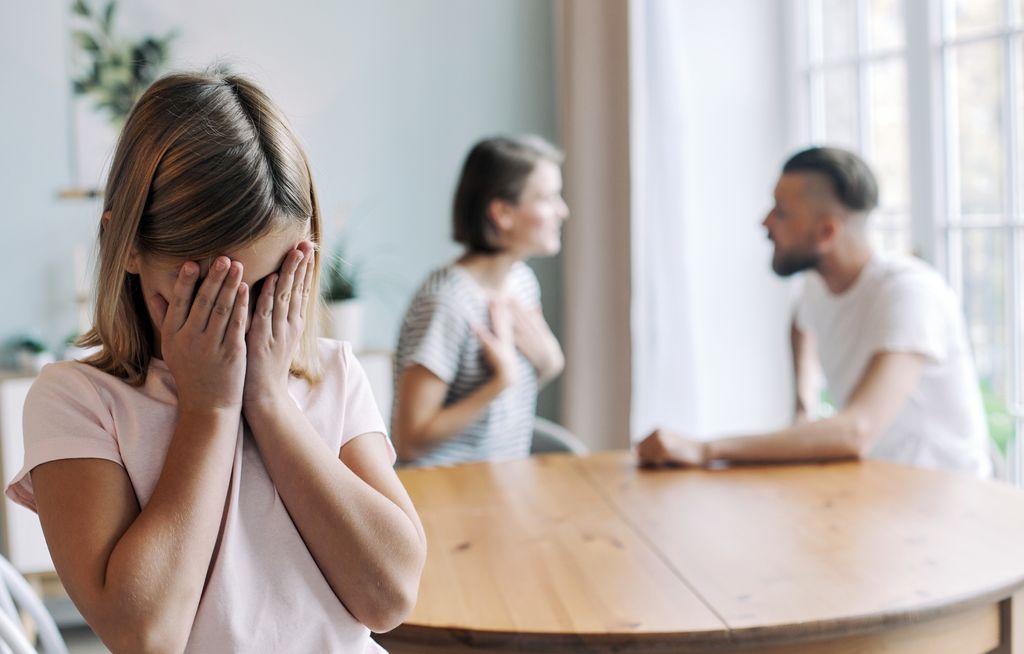 Padres discutiendo en presencia de su hija pequeña que se tapa la cara