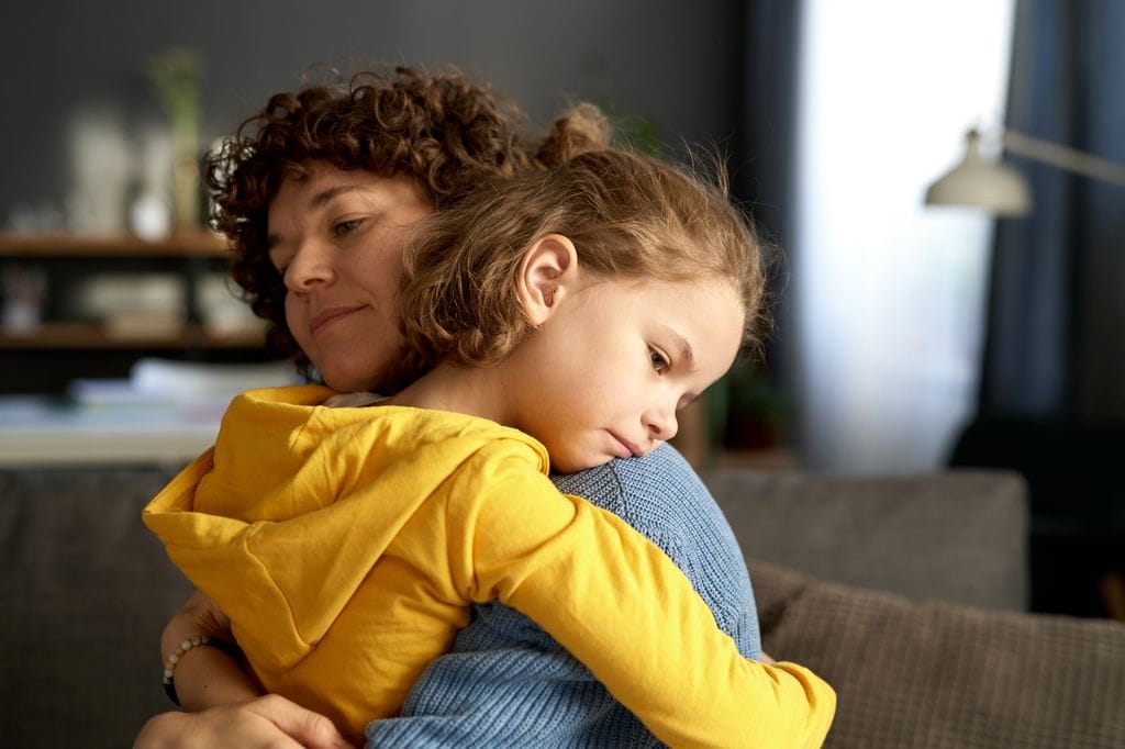 Madre abrazando a una niña pequeña triste