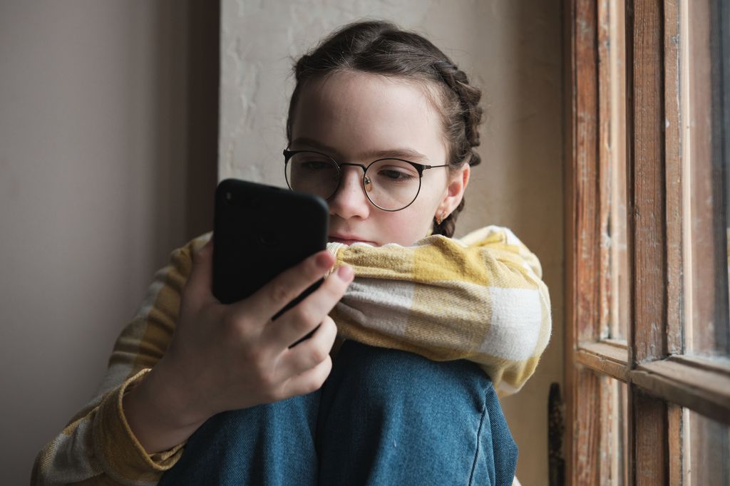 Niña con gafas viendo un móvil