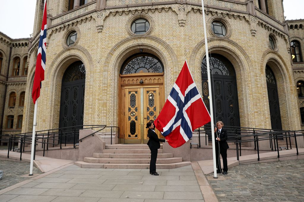 El personal iza la bandera nacional de Noruega a media asta antes del inicio de la ceremonia de juramento del nuevo rey ante la Constitución, frente al Parlamento, en Oslo, el 1 de septiembre de 2026