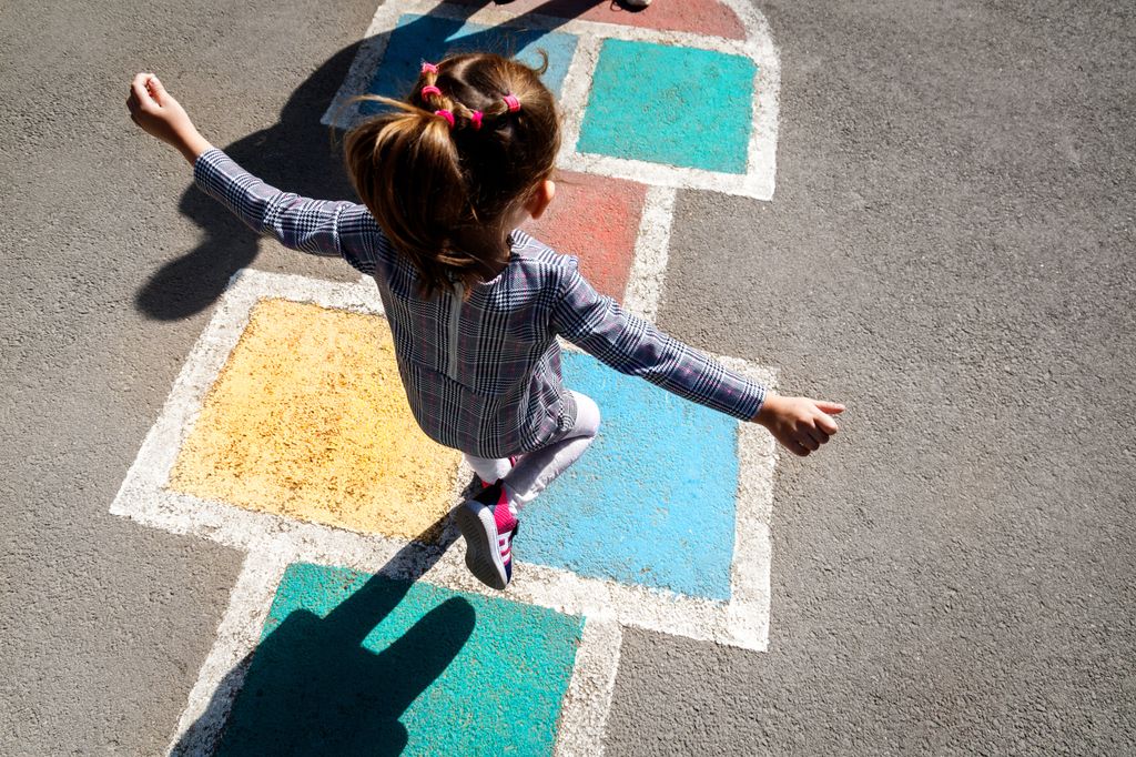 Niña saltando en una rayuela en la calle
